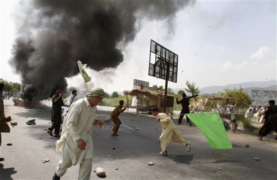 Afghans pelt stones at an election signboard and burn tires blocking a highway, in reaction to a small American church's plan to burn copies of the Quran, at Jalalabad, east of Kabul, Afghanistan, Friday.